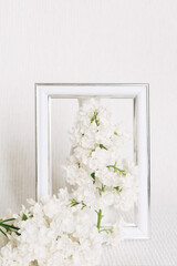 Bouquet of white lilacs in a white photo frame. white interior.