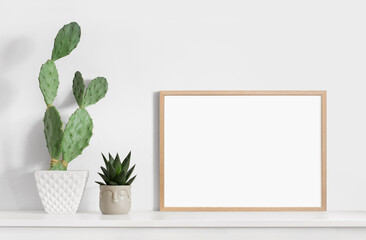 Empty horizontal wooden frame mockup in modern minimalist interior with plant in trendy vase on...