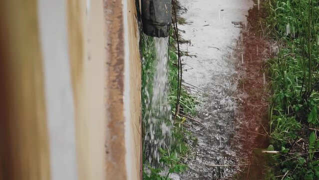 Water during the rain flows in a large jet from the downpipe. Shooting in the rain