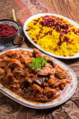Traditional Persion lamb ragout xoresht-e badenjan with vegetable served with steamed saffron rice and berberis as close-up on a classic design plate