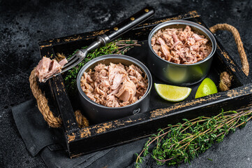 Open Can with Preserved tuna fillet meat. Black background. Top view
