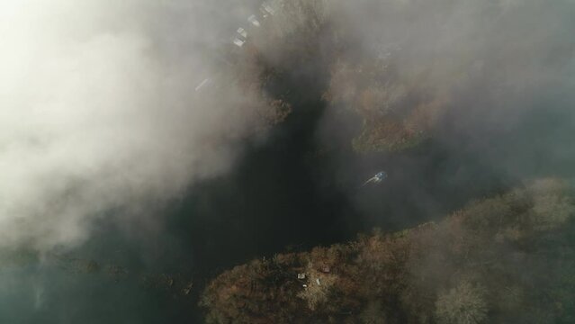 A fishing boat spits along the Desna river in the fog. Aerial. Ukraine. Kyiv. 