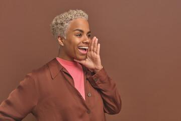 Young cheerful beautiful African American woman millennial raised hand to mouth to shout out loud...
