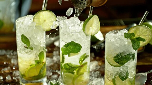 Super slow motion of preparing mojito drink with speed motion. Filmed on high speed cinema camera, 1000 fps, placed on high speed cine bot. Bar with bottles on background.