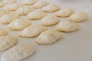 Fototapeta na wymiar Making homemade buns from yeast dough on white countertop, using potatoes as filling