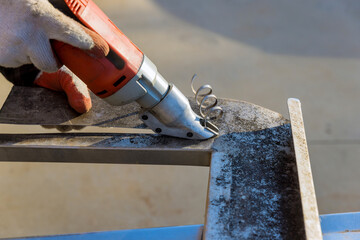 Worker cutting metal using gauge double shear electric scissors