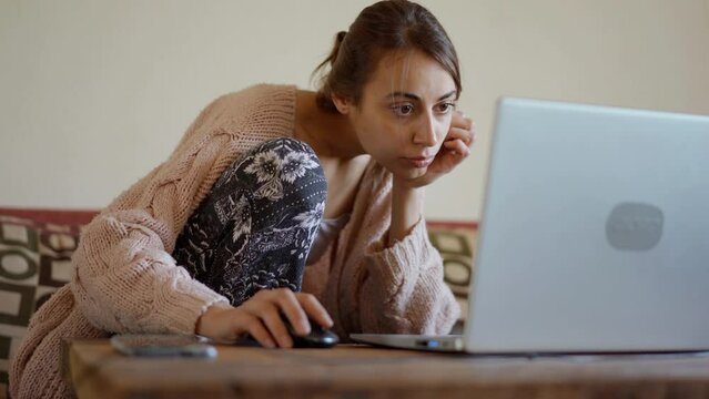 woman sits at home on couch with laptop, working remotely, shopping online. freelancer, remate work, workplace at home