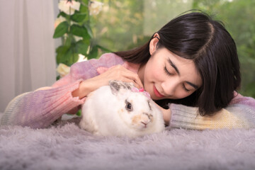 Friendly beautiful woman with her rabbit, human and pet relation concept, furry bunny with solfly touch and love.