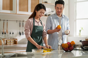 young asian couple talking chatting in kitchen