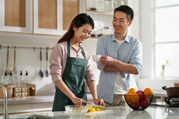 young asian couple talking chatting in kitchen