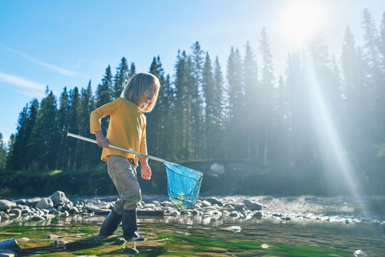 Preschooler with a fishing net by river