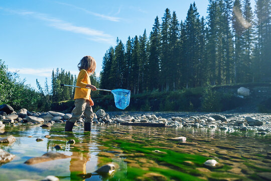 Preschooler with a fishing net by river