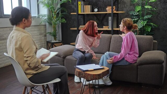 Mother and daughter argue on couch in psychologist office