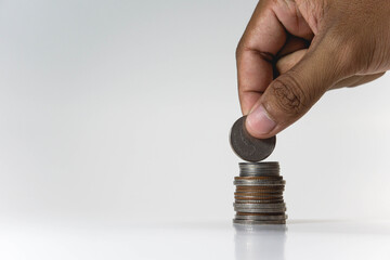 Male's hand putting money coin on stack. Saving money, investing, finance and investment concept