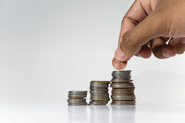 Male's hand putting money coin on stack. Saving money, investing, finance and investment concept