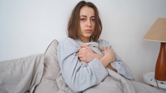 young woman lies alone on bed at home, cold and sick. illness, cold, virus, doctor's call at home, consultation with a doctor by phone