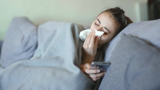 young woman lies alone on bed at home, cold and sick. illness, cold, virus, doctor's call at home, consultation with a doctor by phone
