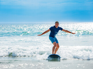 Man learns to surf waves balancing on surfboard