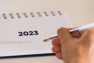 person writing in an agenda for 2023