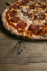 Delicious hot meat pizza with prosciutto and salami on a wooden table. High quality photo