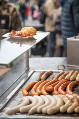 Variety of German sausages on the cooking grate of a hot-dog stall