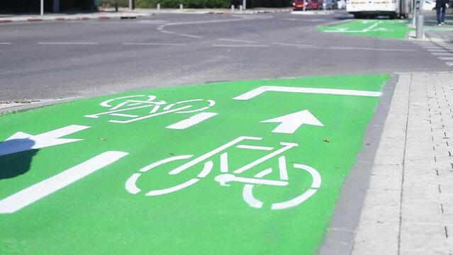 Green bicycle lane dedicated of separate for move cyclists on road in city. Tricycle rides on dedicated lane. White arrows show directions for movement. Signs on road ensures safety of people's.