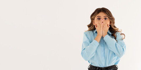Young shocked woman closed her mouth with crossed hands and wide opened eyes. Horizontal photo of...