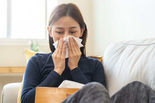 Sick, influenza asian young woman, girl headache have a fever, flu and check measure body temperature, feel illness sitting on sofa bed at home. Health care person on virus, covid-19.