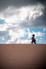 African woman with scarf walking in the dunes.