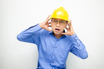 asian male construction worker or engineer in blue shirt and safety yellow helmet shows expresion of anger, furious and dissapointment isolated over white. stressed over work concept
