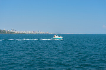 A small speedboat floats on the sea against the backdrop of the city of Istanbul