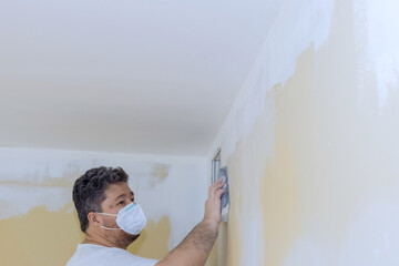 Worker sanded drywall mud using sand trowel at time of renovating house in room