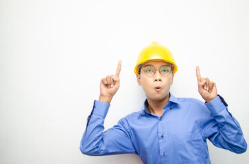 side view of A happy, shocked asian consrtuction worker in blue shirt and yellow safety helmet pointing finger and presenting something ads. 