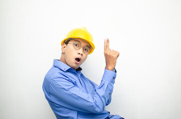 asian construction worker wearing yellow safety helmet and smiling and pointing finger with happy and shocked expression. billboard model advertisment concept. construction worker presenting something