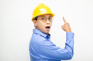 side view of A happy, shocked asian consrtuction worker in blue shirt and yellow safety helmet pointing finger and presenting something ads. 