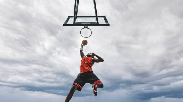 Basketball street player making a rear slam dunk - Athletic male training outdoor - Sport and competition concept