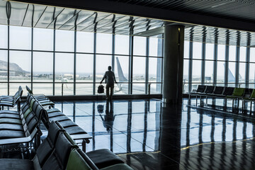 One man standing at the airport gate waiting his flight with delay or canceled. Traveler people lifestyle in indoor leisure activity. One tourist with backpack wait to fly with airplane for vacation