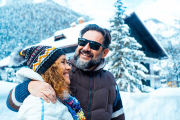Happy young mature couple of tourist enjoy together winter holiday vacation time. Home chalet and mountains with trees in background. Travel man and woman concept lifestyle Love and friendship outdoor