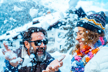 Man and woman have fun together with snow in mountains holiday vacation together. Happy couple in funny leisure activity outdoor together in winter cold season. Enjoyment and love lifestyle people