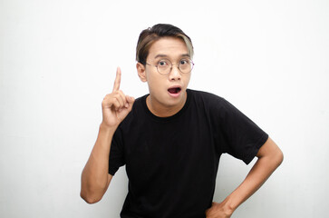 A cheerful, ecstatic Asian man wears a casual black t-shirt, pointing to copy space and presenting and displaying goods. billboard model advertisment concept. A man with a wow expression displaying so