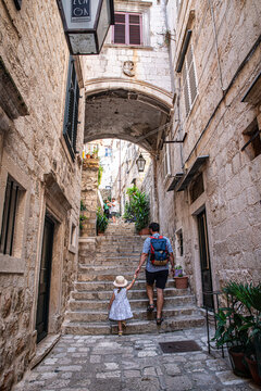 Fototapeta Father and little daughter walking on narrow streets of Mediterranean town.