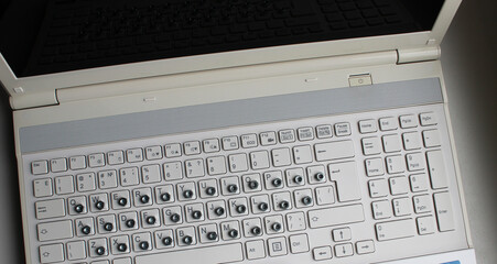 Top view of laptop with iron nuts overlay a russian letters on keyboard buttons
