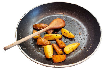 Cooking traditional village food. Fried potatoes in frying pan and wooden spoon.