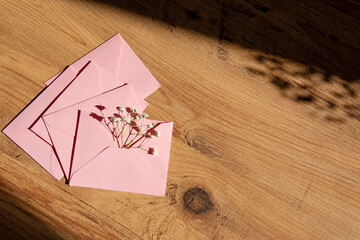 pink envelopes with flowers on a wooden background.