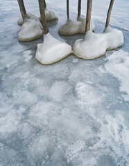 Massive ice formations on the wooden pillars of the pier in winter on a frozen lake, massive ice froze in winter on a lake