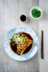 Traditional Japanese barbecue swordfish teriyaki steak with lemon grass and wakame salad in a spicy...