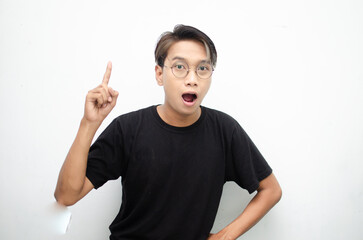 A cheerful, ecstatic Asian man wears a casual black t-shirt, pointing to copy space and presenting and displaying goods. billboard model advertisment concept. A man with a wow expression displaying so