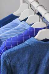 hangers with clothes, wardrobe shirt jacket blue. storing clothes or shopping. stylist selection of look for work and walking. fashion and casual wear