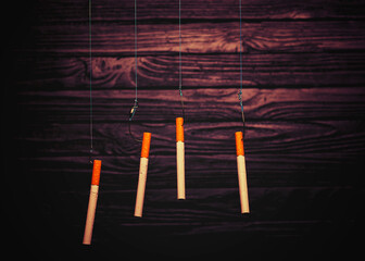 cigarettes on fish hooks. wooden background in retro style. dependence on cigarettes.