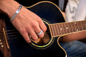 Young man is playing guitar while his girlfriend is singing. Detail of hand on guitar strings. - 565679016